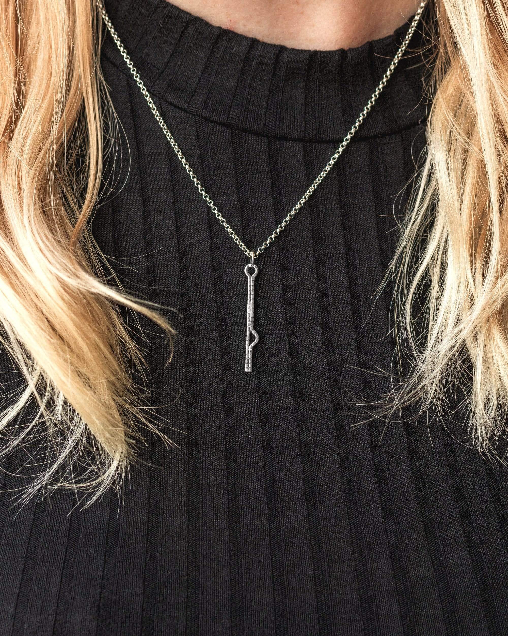 Close-up of a model wearing the vertical shRNA necklace in sterling silver, highlighting its scientific inspiration. Close-up of a model wearing the vertical shRNA necklace in sterling silver, highlighting its scientific inspiration.