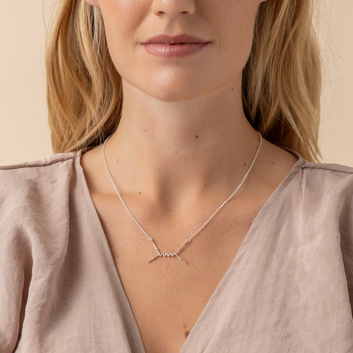 Model wearing the Feynman Scattering Necklace, showcasing its sleek, scientific design in sterling silver.