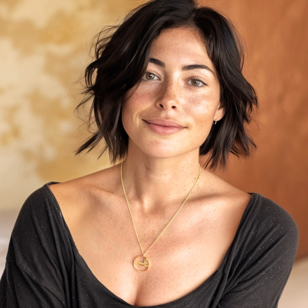 Smiling woman with short dark hair wearing the gold vermeil CRISPR necklace, styled with a black top.