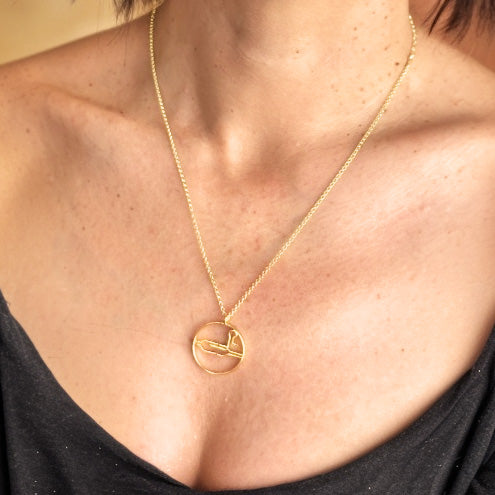 Close-up of a woman’s neck and chest wearing the gold vermeil CRISPR necklace on a delicate chain.