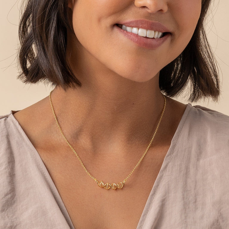 Close-up of 18K gold vermeil DNA necklace on model, showing double helix design.