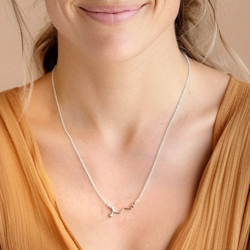 Close-up view of the GABA necklace resting on a woman's neck, highlighting the detailed molecular structure and fine silver chain.