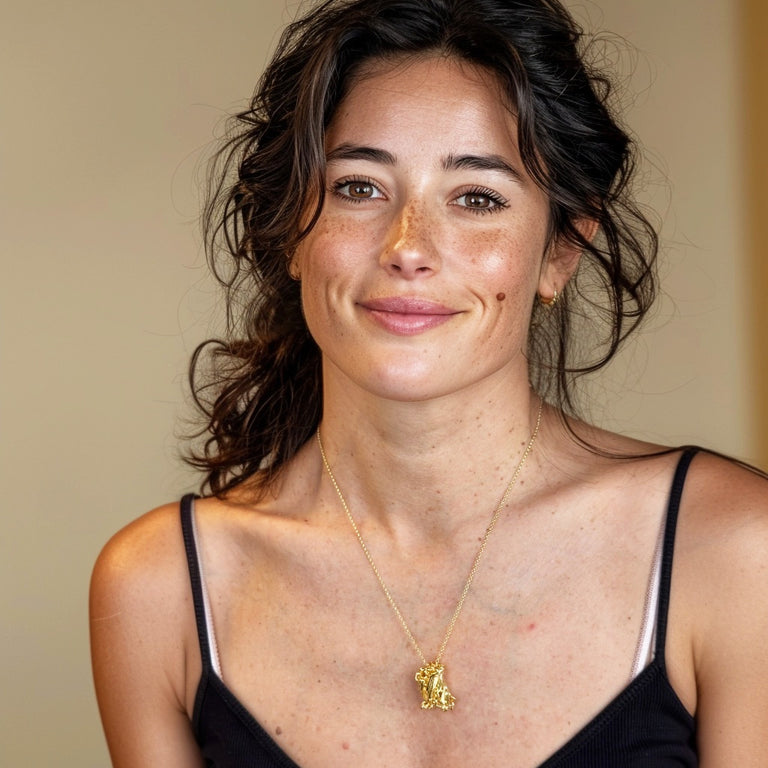 Smiling woman wearing the GFP gold vermeil necklace with a black top, highlighting the pendant’s intricate molecular design and elegant shine.