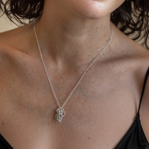Woman wearing silver Human Growth Hormone molecule necklace – elegant science jewelry celebrating endocrinology and molecular biology.