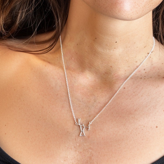 Woman wearing the Orion Necklace, featuring a delicate constellation pendant representing Orion’s Belt, styled with a minimalist silver chain.
