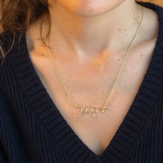Close-up view of a woman wearing the gold vermeil T4 thyroid hormone necklace, photographed from the collarbone area to show the pendant’s size and delicate chain.