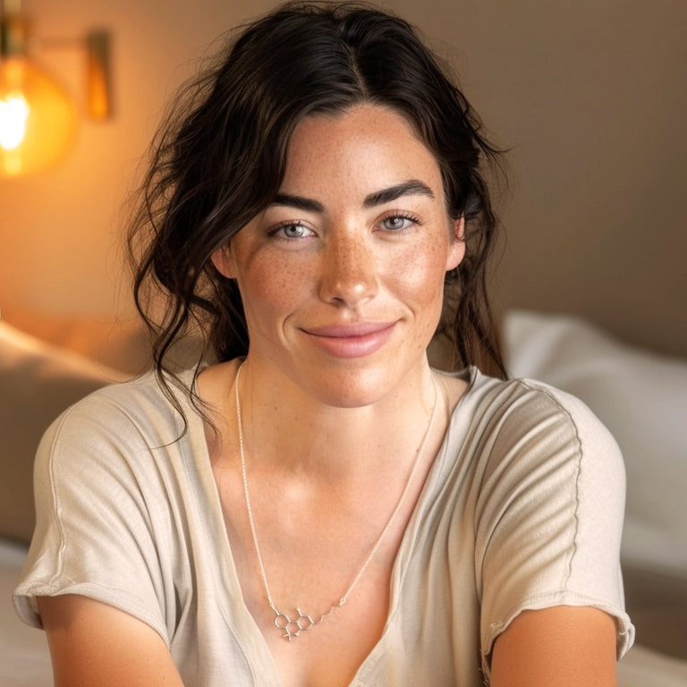 Smiling woman wearing the sterling silver THC molecule necklace, styled casually with a beige top, highlighting its everyday wearability