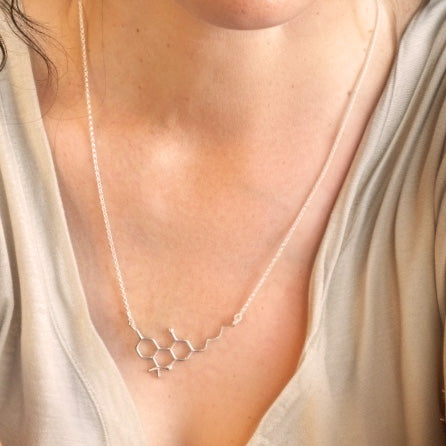 Close-up of the THC molecule necklace in sterling silver worn on a woman’s chest, showing the pendant’s minimalist molecular design.