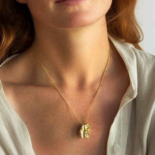 Close-up of a woman wearing the T-Rex skull necklace in gold vermeil, highlighting the pendant’s detailed design against her chest.