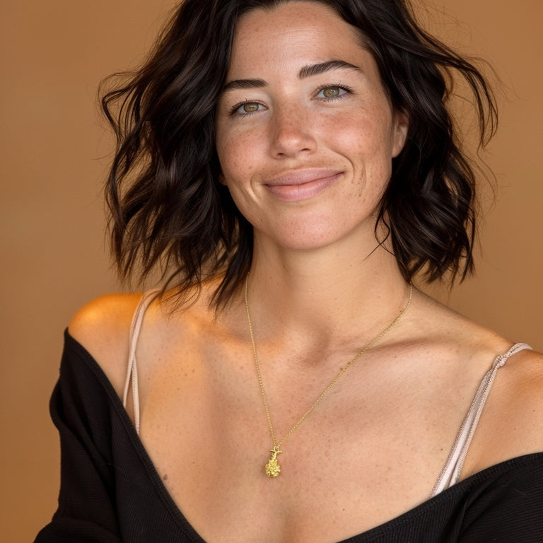 Smiling woman wearing the gold vermeil alveolus necklace, styled casually with a black top and natural makeup.