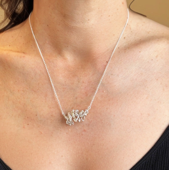 Close-up of silver ankyrin protein necklace on neckline, molecular biology inspired jewelry gift for scientists.