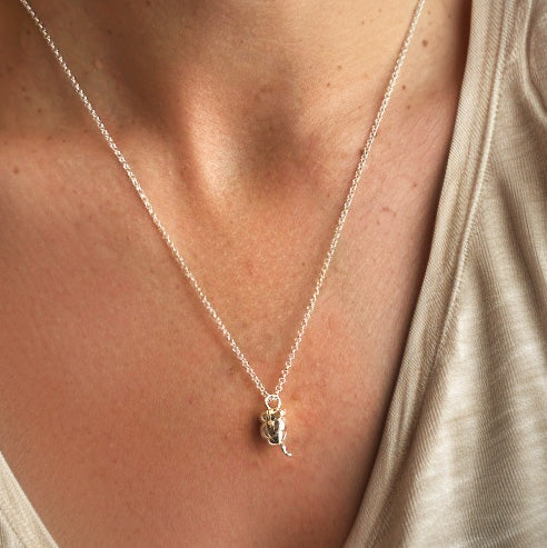 A cropped image showing a person wearing the appendix necklace in gold vermeil, styled with a v-neck shirt for a minimalist look.