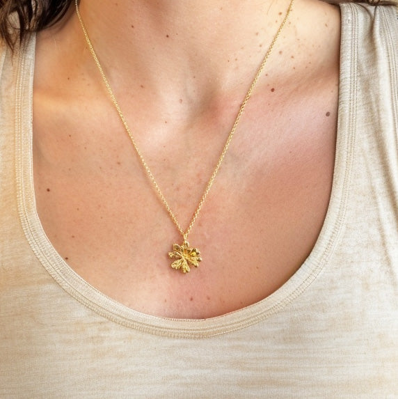 A close-up view of the Arabidopsis necklace worn on a woman’s neck with a beige tank top, highlighting the pendant’s details and size.