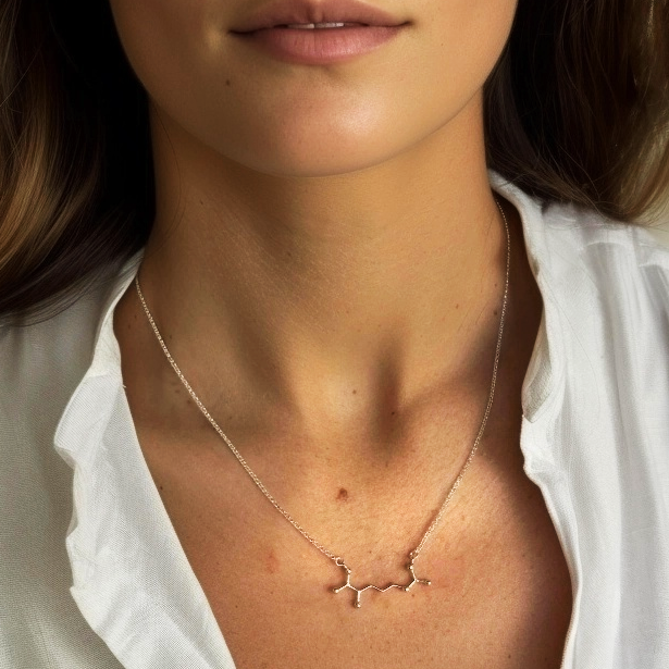 Close-up of the Arginine Necklace worn by a model, showcasing the elegant molecular design resting on her collarbone.