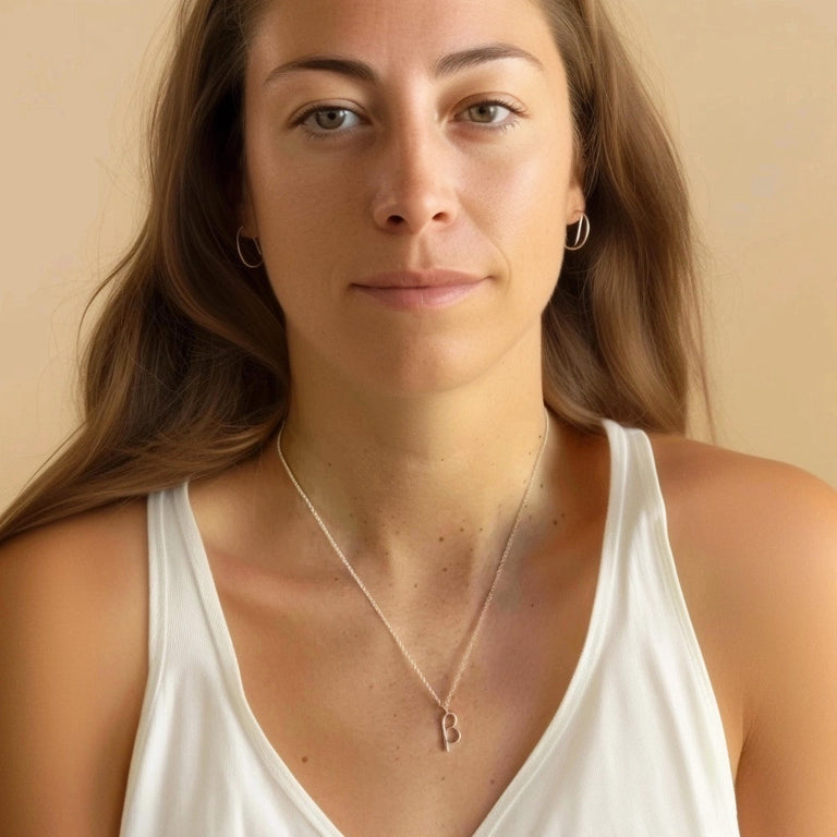 Woman with long brown hair wearing the beta necklace, shown in a portrait view against a neutral background