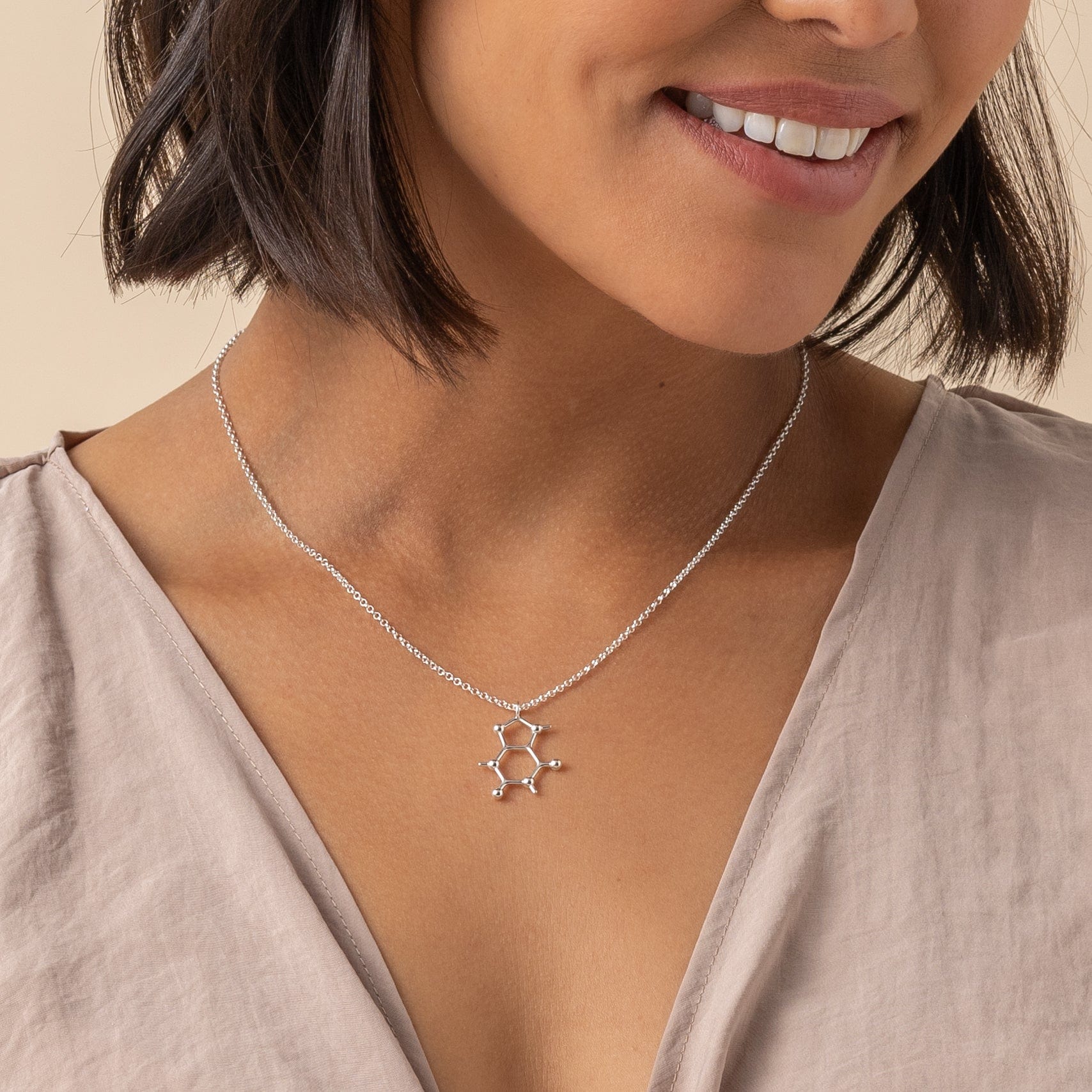 Model wearing the caffeine molecule necklace, highlighting how it pairs elegantly with casual and professional outfits.