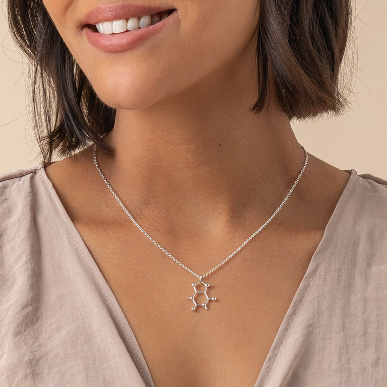 Side view of the necklace on a model, emphasizing the detailed molecular structure and delicate silver chain.