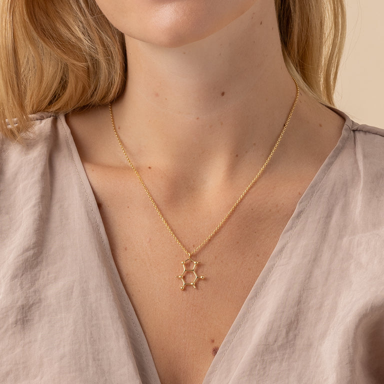 Woman wearing gold vermeil caffeine necklace – stylish nod to caffeine lovers and science geeks.