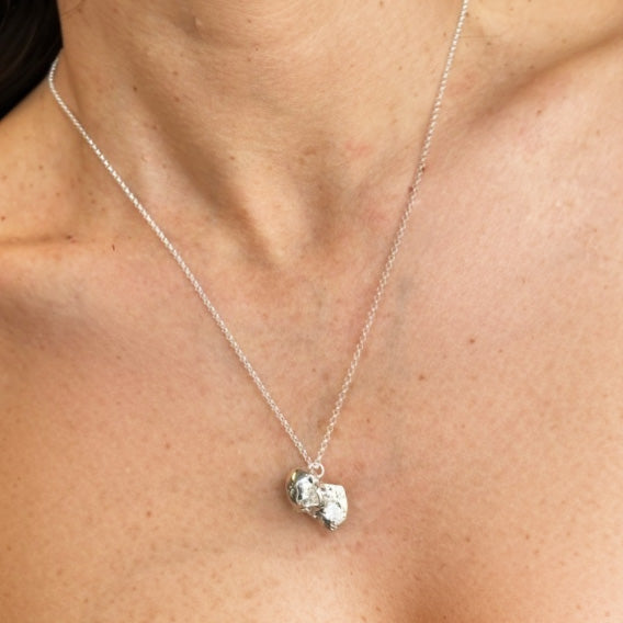 Woman wearing a chimpanzee skull pendant necklace in sterling silver, symbolizing intelligence, evolution, and conservation – science-inspired jewelry.
