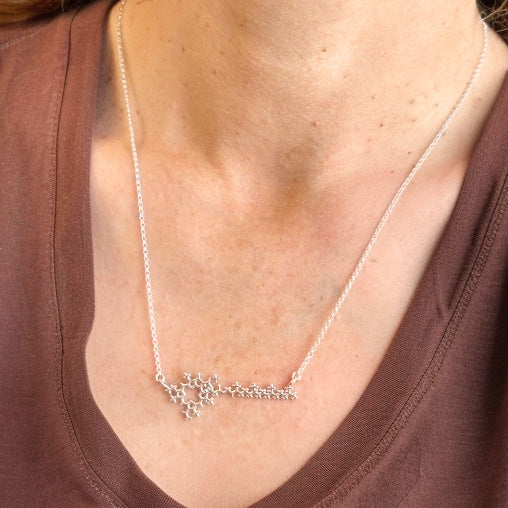 Close-up view of a person’s neck and upper chest wearing the silver chlorophyll molecule necklace on a fine chain.