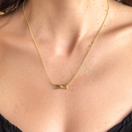 Close-up of the gold vermeil chromosome necklace resting on a woman’s collarbone, highlighting the detailed chromosome-shaped pendant.