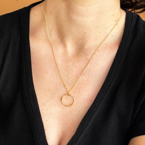 Close-up view of the Cloning Vector Necklace in gold vermeil worn around the neck, styled with a black V-neck top.