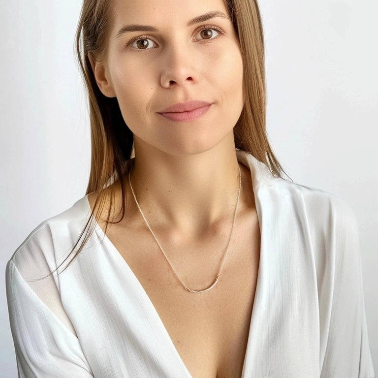Smiling woman wearing the Collagen Necklace with a white blouse, highlighting the necklace’s minimalist and refined aesthetic.