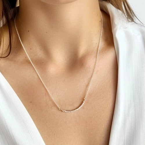 Collagen Necklace worn by a model with a white blouse, showcasing the elegant, science-inspired design around the neck.