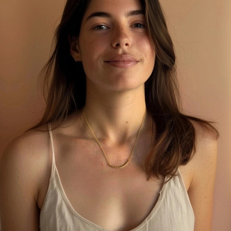 Young woman smiling while wearing the Collagen Necklace in gold vermeil, highlighting its beauty and delicate presence on bare skin.