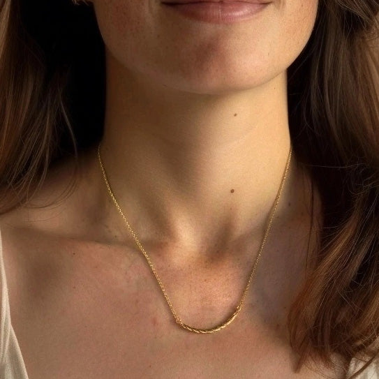 Close-up of a woman wearing the Collagen Necklace in gold vermeil, showcasing its subtle shine and graceful drape along the neckline.