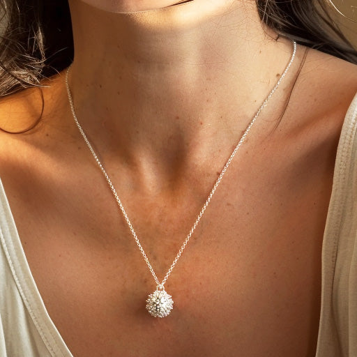 Close-up view of a woman wearing the coronavirus necklace in sterling silver, highlighting the pendant’s intricate design against her skin.