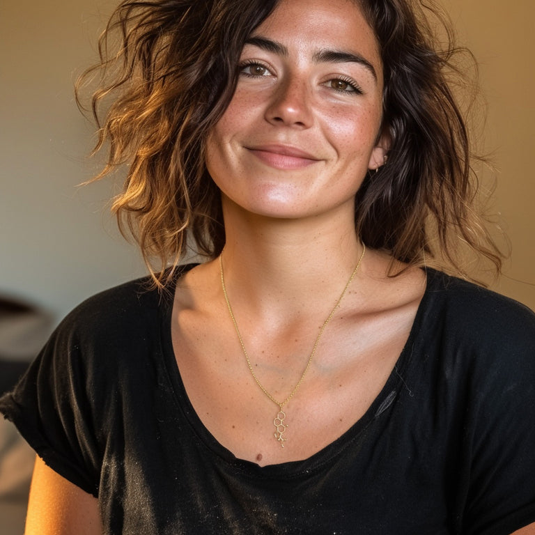 Smiling woman wearing a black shirt, showing the gold vermeil cortisol necklace layered around her neck.