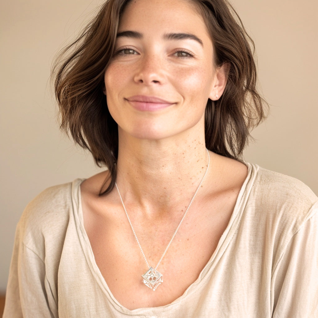 Woman wearing the CubeSat necklace, smiling slightly, with the geometric cube pendant resting at her chest.