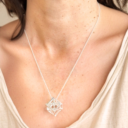Close-up view of the CubeSat necklace worn by a woman, highlighting the cube pendant on a delicate silver chain.
