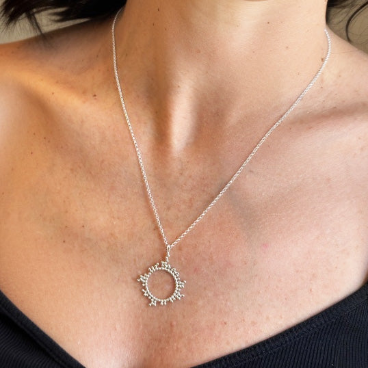 Woman wearing silver cyclo­sporine necklace — molecular jewelry inspired by life-saving transplant medicine, elegant circular molecule pendant representing the immunosuppressant cyclo­sporine compound.