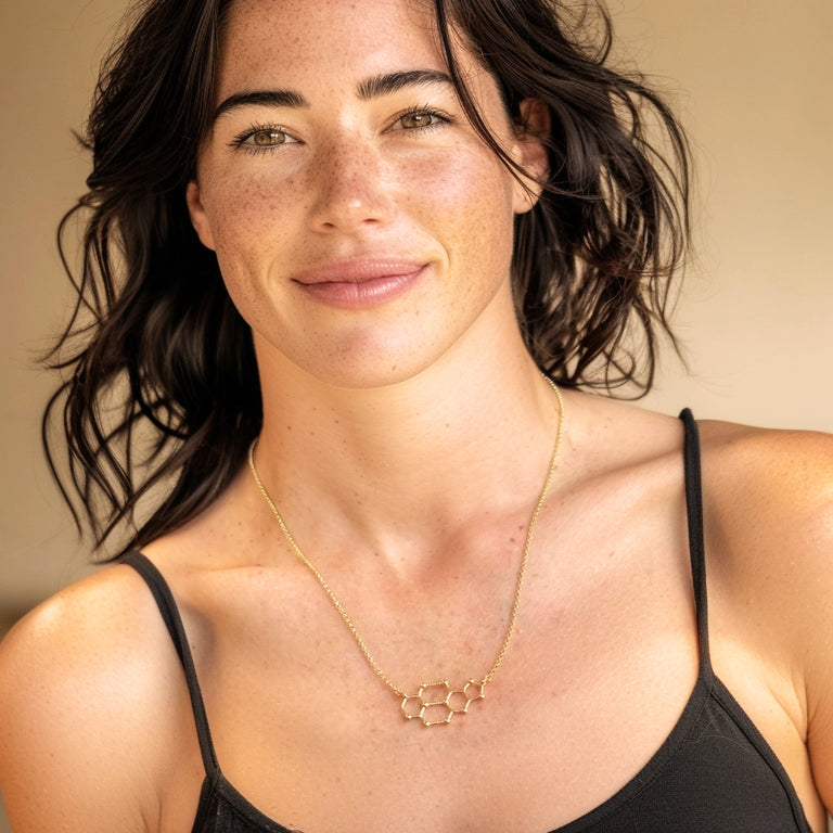 Smiling woman wearing cytosine–guanine DNA necklace in gold vermeil, stylish molecular biology inspired jewelry