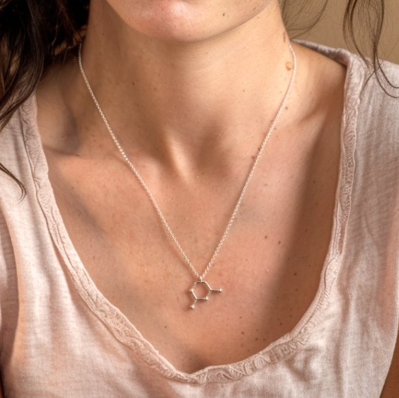 Close-up of a woman wearing the cytosine necklace in silver, styled with a casual light pink t-shirt.