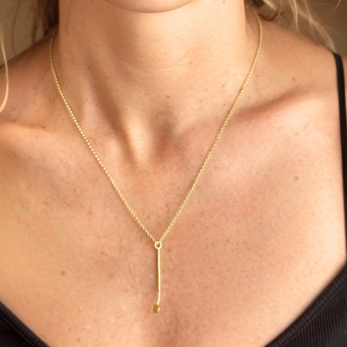 Close-up view of a woman wearing the gold vermeil dental mirror necklace, with the pendant resting at the center of her chest.