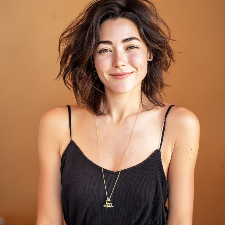 Smiling woman wearing long gold vermeil diamond crystal necklace representing the molecular structure of diamond, elegant science jewelry.