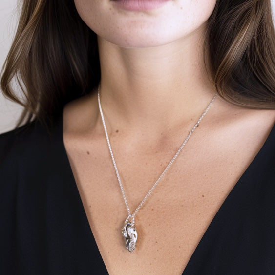 Close-up of a woman wearing the dog skull necklace with a deep neckline, highlighting the pendant’s size and elegant drop.