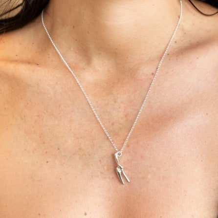 Close-up of silver elbow joint pendant necklace resting on collarbone, anatomical jewelry design by Science Jewelry 18:24.