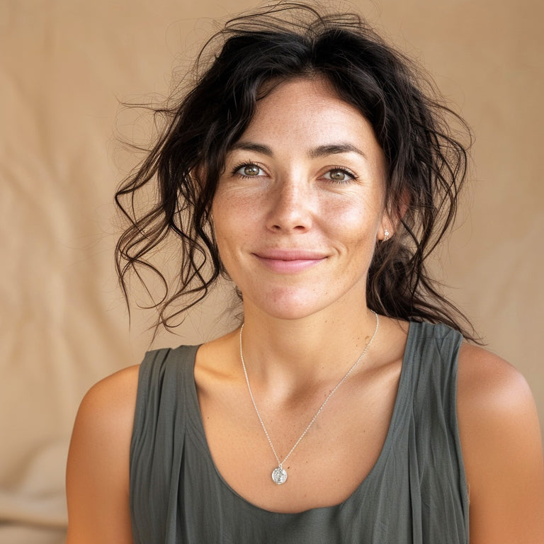 Smiling woman wearing the eosinophil necklace in sterling silver, showing how the pendant sits at chest level against a gray top.