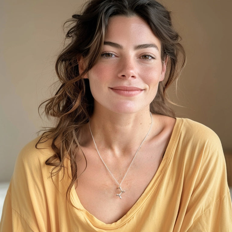 Smiling woman wearing the sterling silver ethanol necklace with a yellow top, highlighting how the jewelry complements everyday outfits