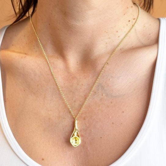 The gold vermeil eye section necklace worn around the neck, displayed against a white tank top, highlighting the pendant’s anatomical eye design.