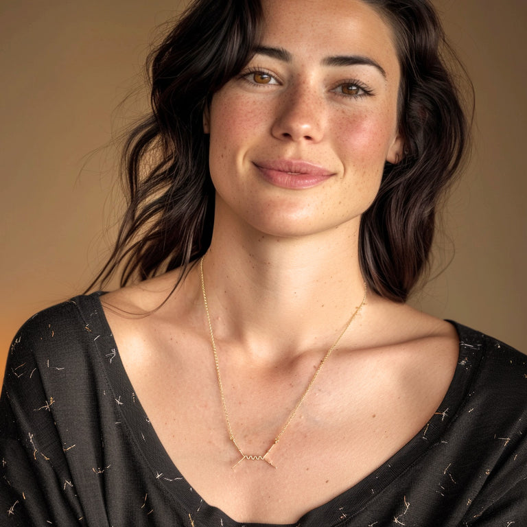 Smiling woman wearing the Feynman Scattering Necklace in gold vermeil, styled with a simple black top to highlight the physics-inspired jewelry.