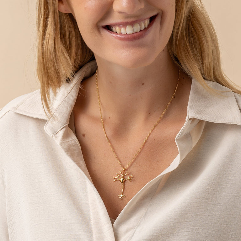 Detailed view of the neuron necklace on a model, highlighting the gold vermeil finish and its delicate neural structure.