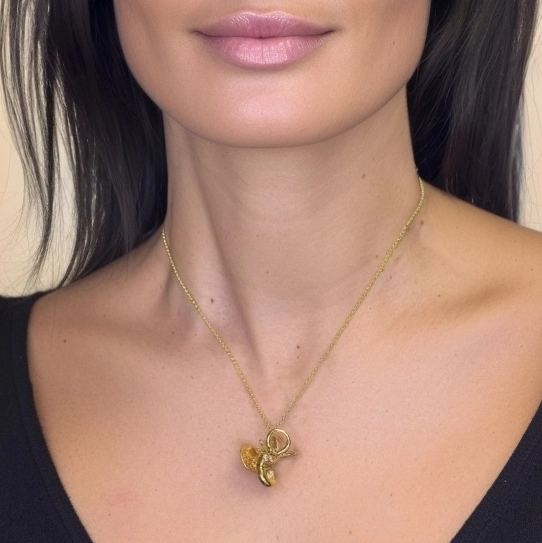 Close-up of woman wearing the gold inner ear anatomy necklace, highlighting the pendant’s intricate design on her chest.
