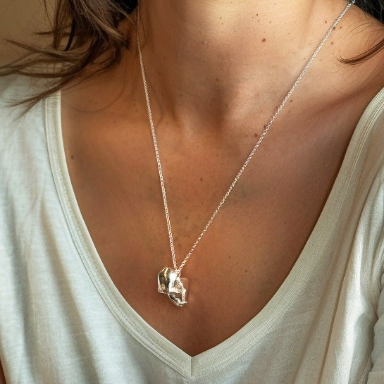 Zoomed-in view of a woman wearing the macaque skull necklace. The pendant rests at mid-chest level, drawing attention to its shiny, detailed design.