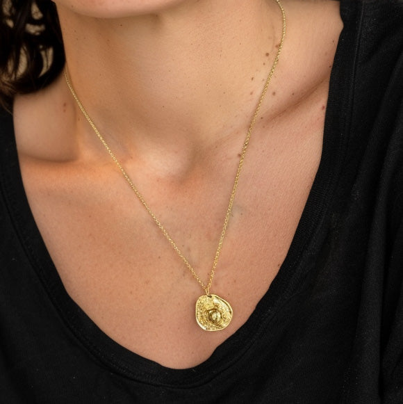 Close-up of the gold vermeil mammalian cell necklace worn around the neck, showing fine chain details and the pendant’s elegant round cell-inspired design.