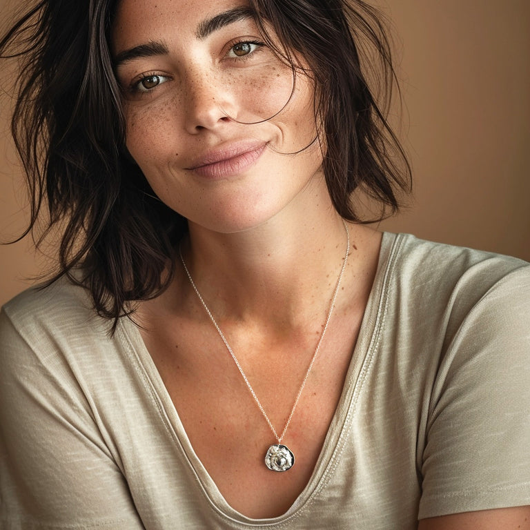 Smiling woman wearing the mammalian cell necklace, styled with a neutral top, showcasing how the pendant hangs around the neck.